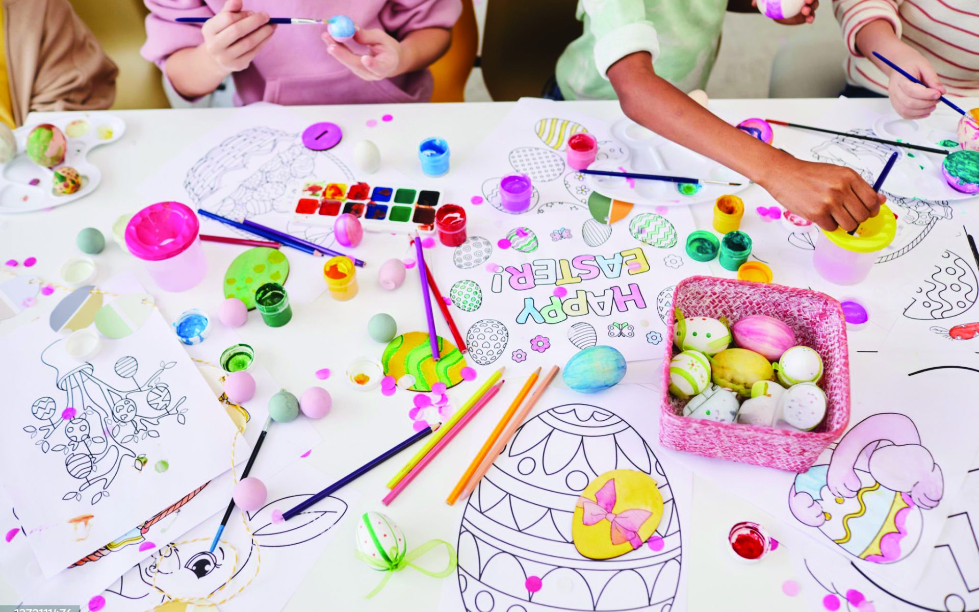 Children painting Easter eggs and coloring books while enjoying art and craft class together.