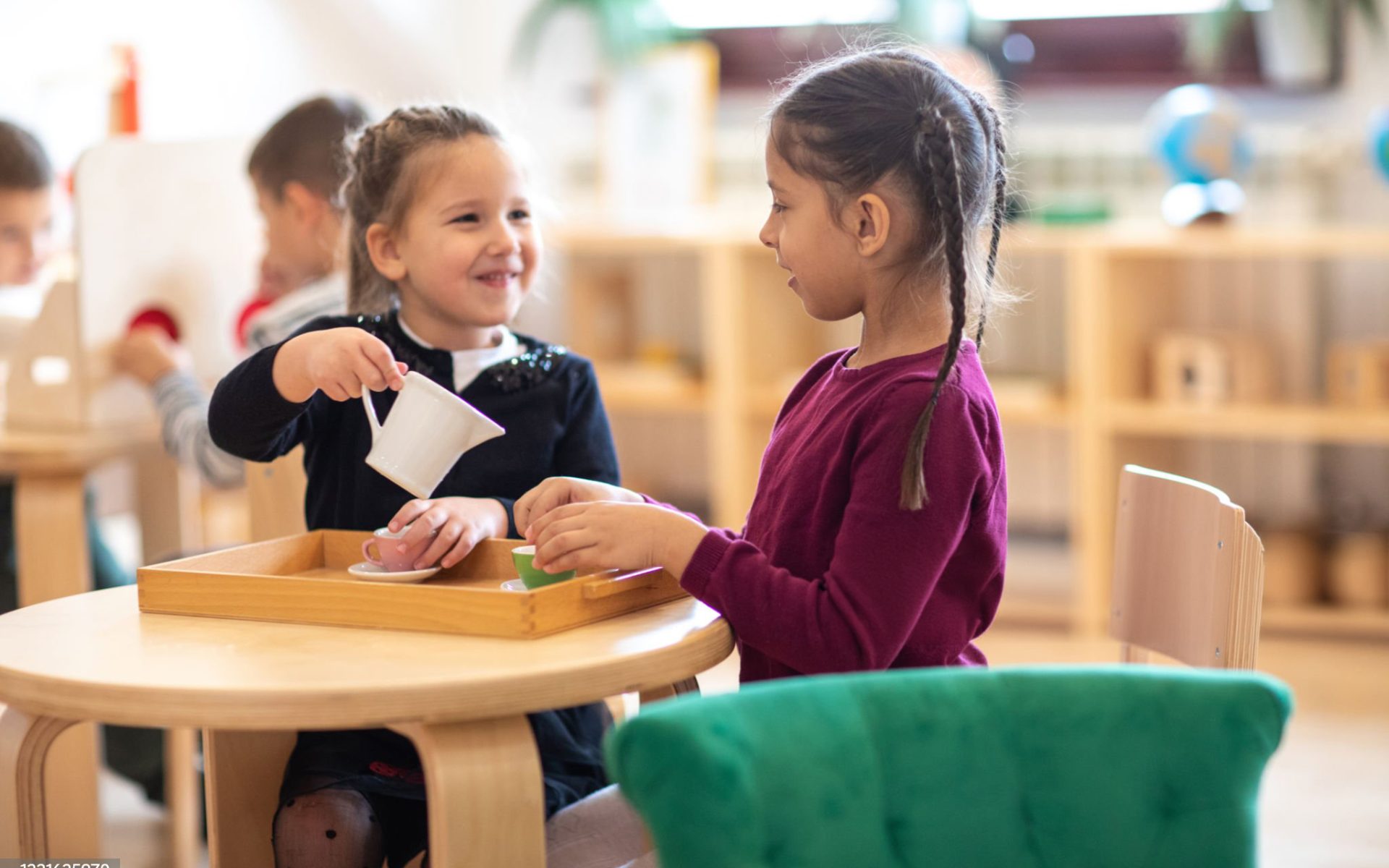 Two children pretending to have tea party in day care playroom